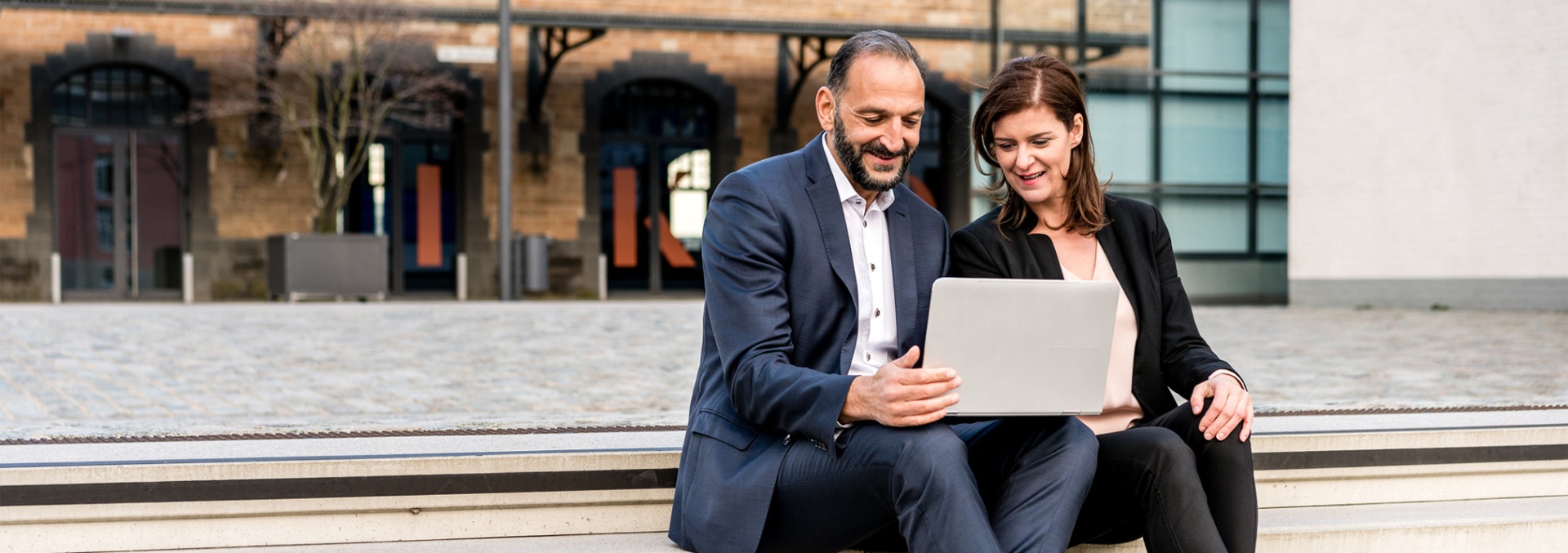 Maja und Tunç Gültekin sitzen mit Laptop und besprechen Inhalte für ein Inhouse-Seminar